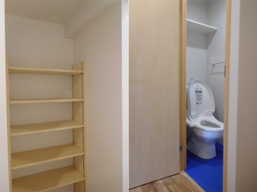 トイレの横には何かと使い勝手の良い可動棚。トイレの床は青。