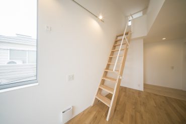 洋室の中央にあるロフトへの階段。木製で、内装と調和しています。