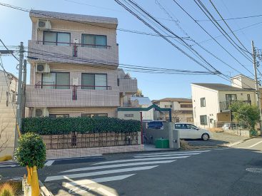 うすくピンクがかかった3階建てのマンション。