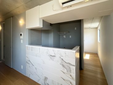 素材感のあるパネルで作られたキッチン。洗濯機もここに。