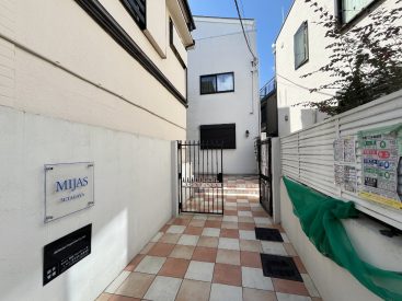 西洋を感じる門扉とレンガのようなタイルの先、白いアパートがあらわれます。