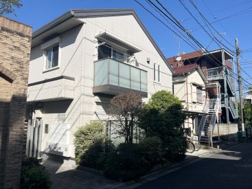 桜新町の街になじむ、白と植栽のマンション。