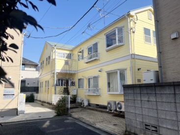 青空のもと、きいろの木造アパート。