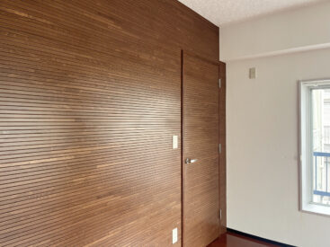 部屋を印象付けるウッドパネル。ドア向こうは寝室に。